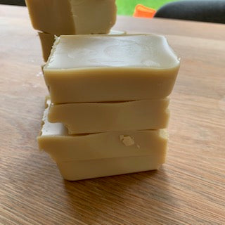Four stacked bars of pale coloured handmade wood polish bars on a wooden tabletop.